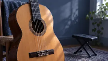 Illustrasjon av en klassisk gitar med bredt gripebrett og en fotstøtte i bakgrunnen.