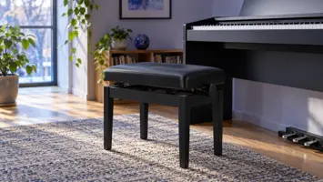 En justerbar pianokrakk med polstret sete ved et piano.
