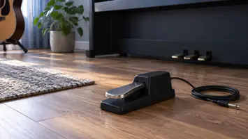 En sustainpedal med metallflate og løs kabel ved et piano.