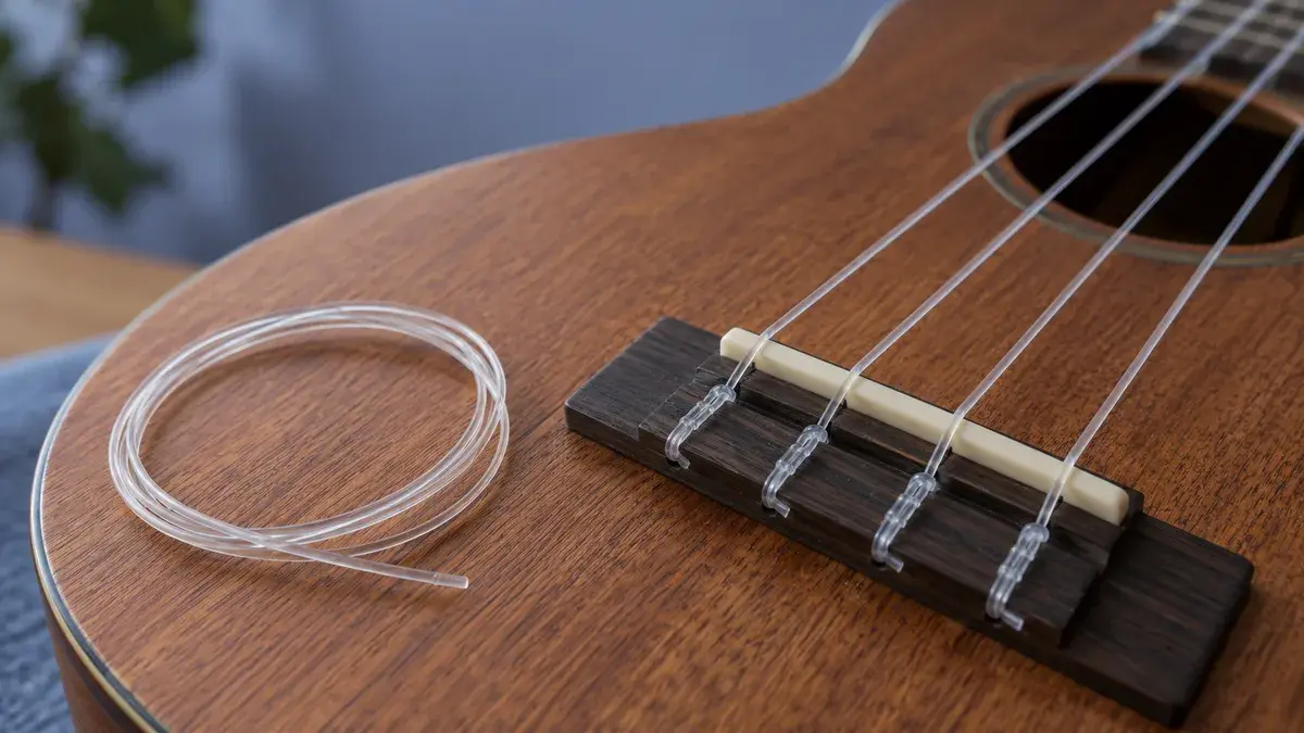 Illustrasjon av strengene over stolen på en ukulele med en ekstra streng ved siden av.